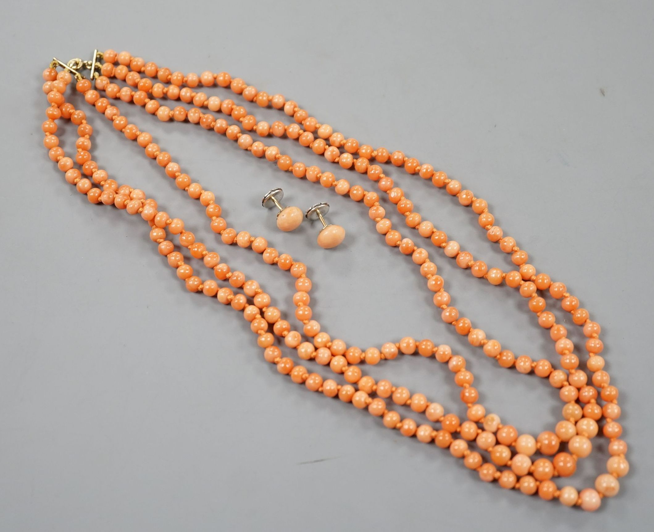 A triple strand coral bead necklace, 46cm and a pair of coral bead earrings.